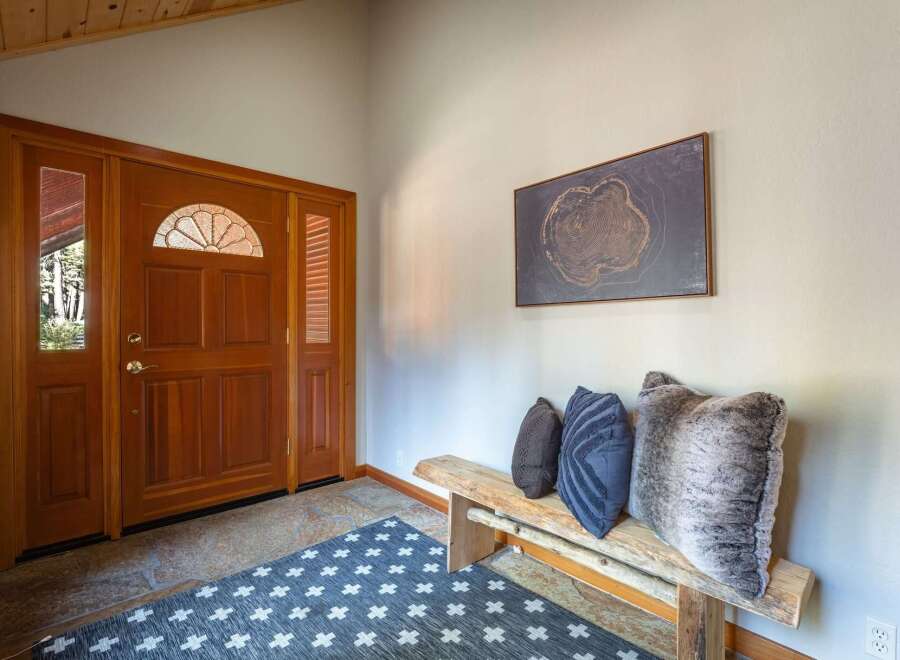 Step into this inviting entryway featuring a beautiful wooden door with a decorative glass transom, setting a warm and welcoming tone.
