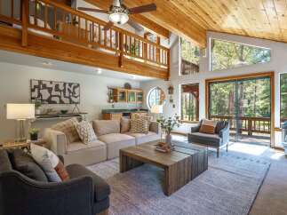 Experience rustic charm in this spacious living room, featuring a vaulted wood-beamed ceiling and a cozy loft overlooking the main area.
