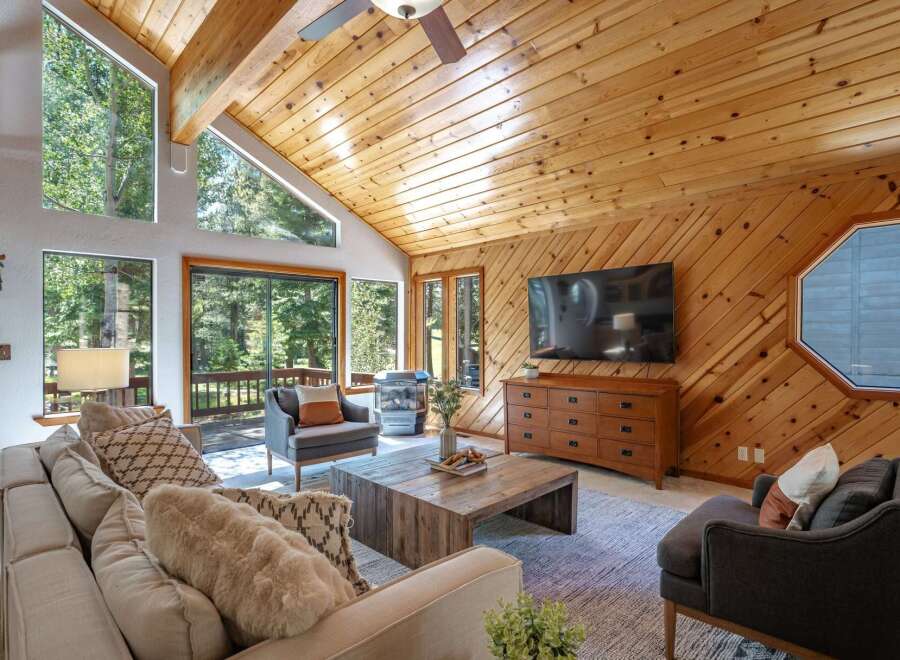 Experience rustic charm in this inviting living room, featuring a vaulted wood-paneled ceiling and a large stone fireplace.