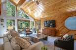 Experience rustic charm in this inviting living room, featuring a vaulted wood-paneled ceiling and a large stone fireplace.