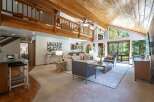Experience rustic charm in this spacious living area featuring a vaulted wood-beamed ceiling and abundant natural light.