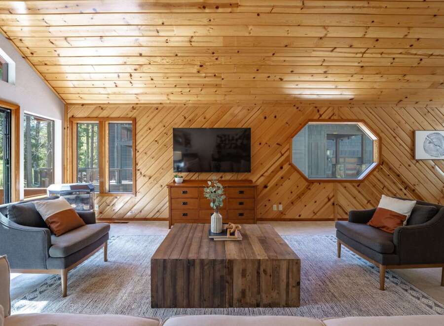 Experience rustic charm in this inviting living room, featuring warm wood-paneled walls and a vaulted ceiling.