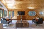 Experience rustic charm in this inviting living room, featuring warm wood-paneled walls and a vaulted ceiling.