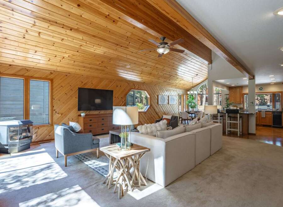 Experience rustic charm in this spacious living area featuring a vaulted wood-paneled ceiling and a cozy gas fireplace.