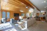 Experience rustic charm in this spacious living area featuring a vaulted wood-paneled ceiling and a cozy gas fireplace.