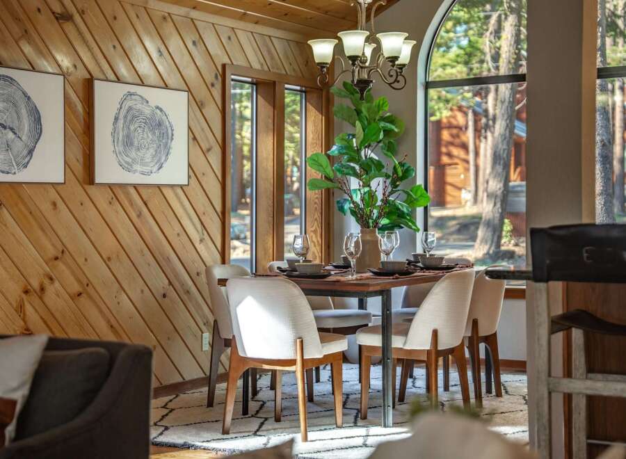 Experience cozy dining in this charming space, featuring a rustic wood-paneled wall and a large arched window that floods the room with natural light.