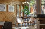 Experience cozy dining in this charming space, featuring a rustic wood-paneled wall and a large arched window that floods the room with natural light.
