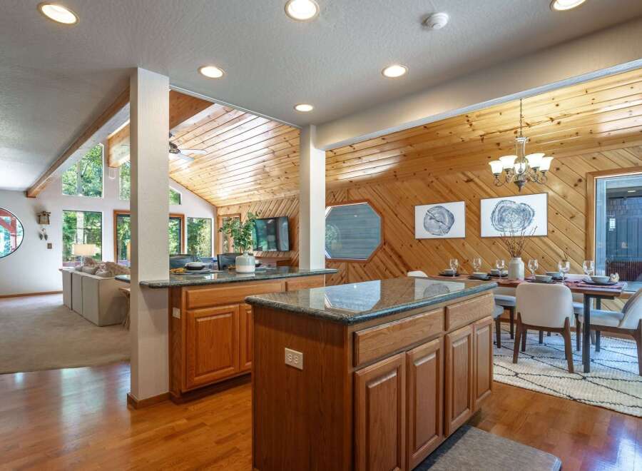 Experience the warmth of this inviting open-concept living space, featuring a stunning wood-paneled ceiling and walls that create a cozy, rustic ambiance.