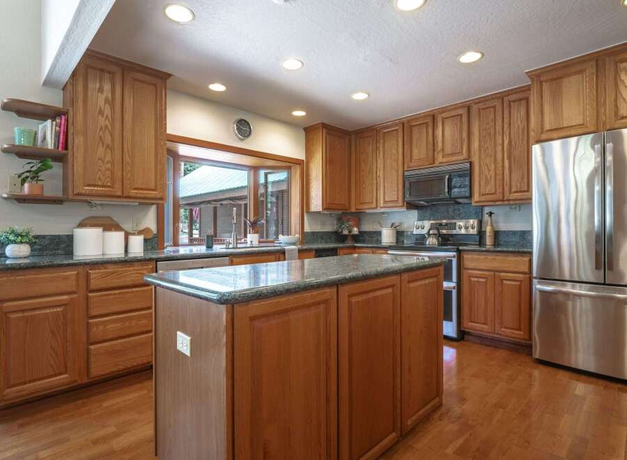 This spacious kitchen boasts beautiful oak cabinetry and granite countertops, offering ample storage and workspace.