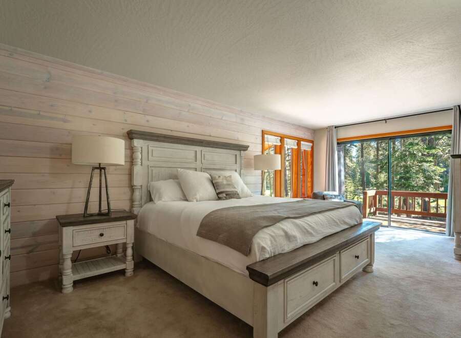 Experience serene mountain living in this charming bedroom, featuring a rustic wood-paneled accent wall and a cozy king-sized bed.