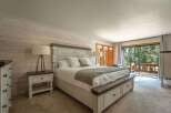 Experience serene mountain living in this charming bedroom, featuring a rustic wood-paneled accent wall and a cozy king-sized bed.
