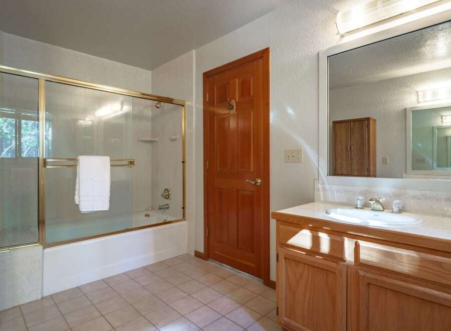 This bathroom features a spacious bathtub with a glass enclosure and a white towel neatly folded on the rack.
