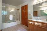 This bathroom features a spacious bathtub with a glass enclosure and a white towel neatly folded on the rack.