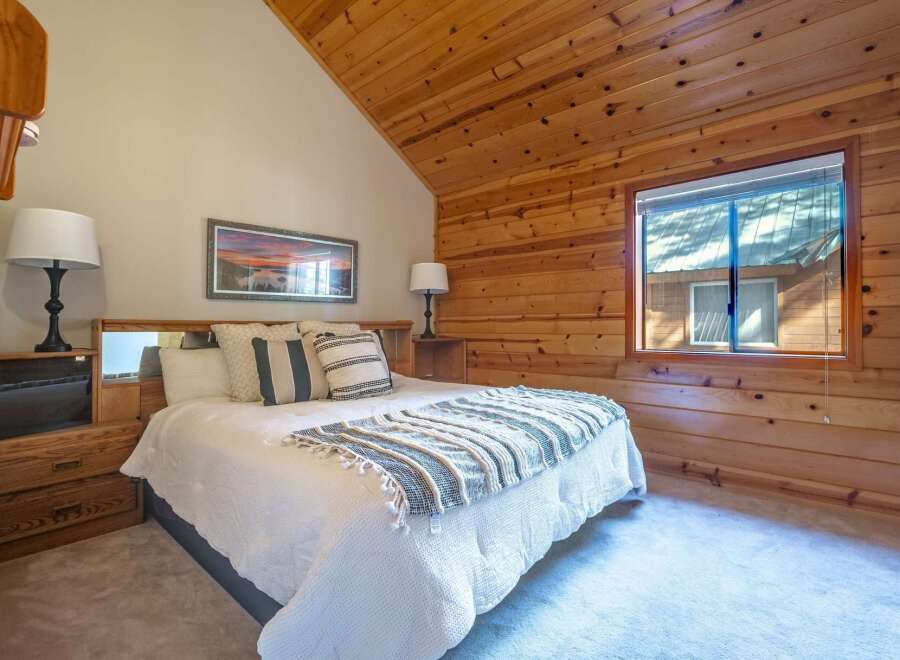 Experience rustic charm in this cozy bedroom, featuring a comfortable bed adorned with plush pillows and a decorative throw.