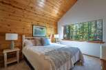 Experience rustic charm in this cozy bedroom, featuring warm wood-paneled walls and a vaulted ceiling.