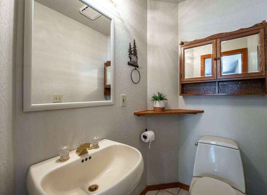 This charming bathroom features a pedestal sink with elegant brass fixtures and a large vanity mirror.