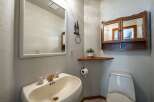 This charming bathroom features a pedestal sink with elegant brass fixtures and a large vanity mirror.