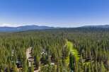 Experience the ultimate mountain lifestyle with this stunning aerial view showcasing a beautiful golf course nestled amidst a dense pine forest.