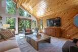 Experience rustic charm in this inviting living room, featuring a vaulted wood-paneled ceiling and a large stone fireplace.