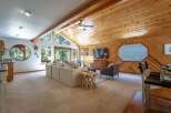 Experience rustic charm in this spacious living area, featuring a vaulted wood-paneled ceiling with exposed beams and a cozy seating arrangement.