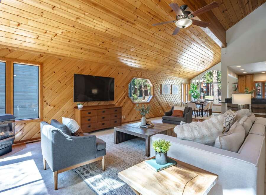 Experience rustic charm and modern comfort in this inviting living space, featuring a vaulted wood-paneled ceiling and a cozy fireplace.