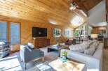Experience rustic charm and modern comfort in this inviting living space, featuring a vaulted wood-paneled ceiling and a cozy fireplace.