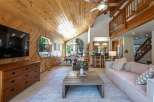 Experience rustic charm in this stunning mountain home featuring a vaulted wood-paneled ceiling and a unique hexagonal window offering picturesque views.