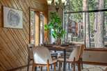 Experience cozy dining in this charming space, featuring a rustic wood-paneled accent wall and a large window offering serene forest views.