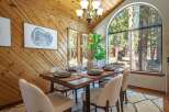 Experience rustic charm in this dining room featuring a large arched window with stunning forest views.