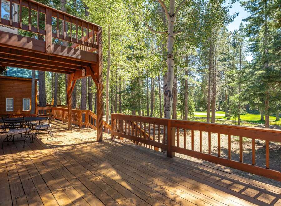 Enjoy the serene mountain lifestyle from this expansive wooden deck, perfect for outdoor dining and relaxation amidst towering trees.