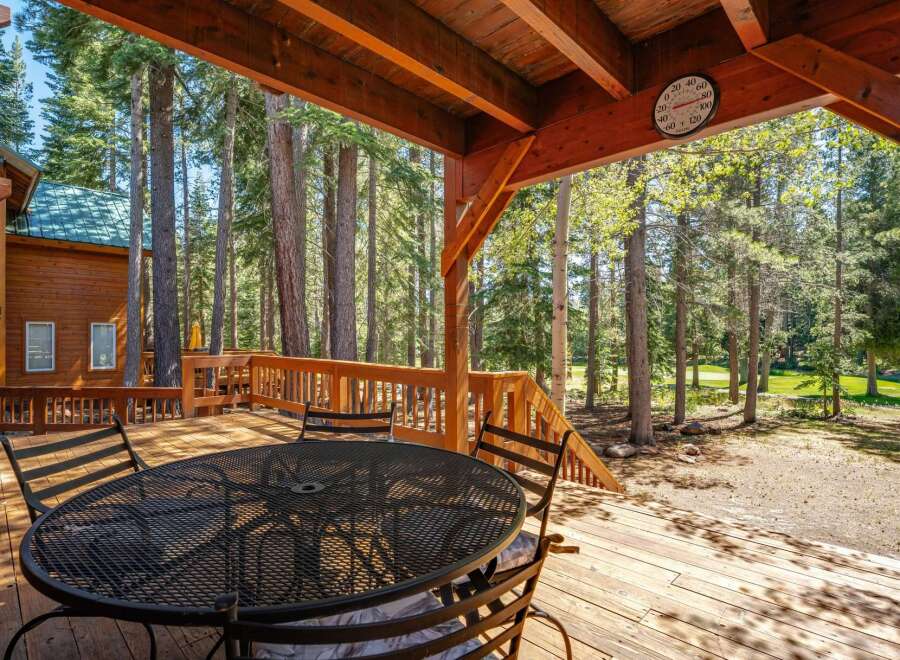 Enjoy the serene mountain lifestyle from this expansive wooden deck, perfect for outdoor dining and relaxation amidst towering pine trees.