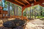 Enjoy the serene mountain lifestyle from this expansive wooden deck, perfect for outdoor dining and relaxation amidst towering pine trees.