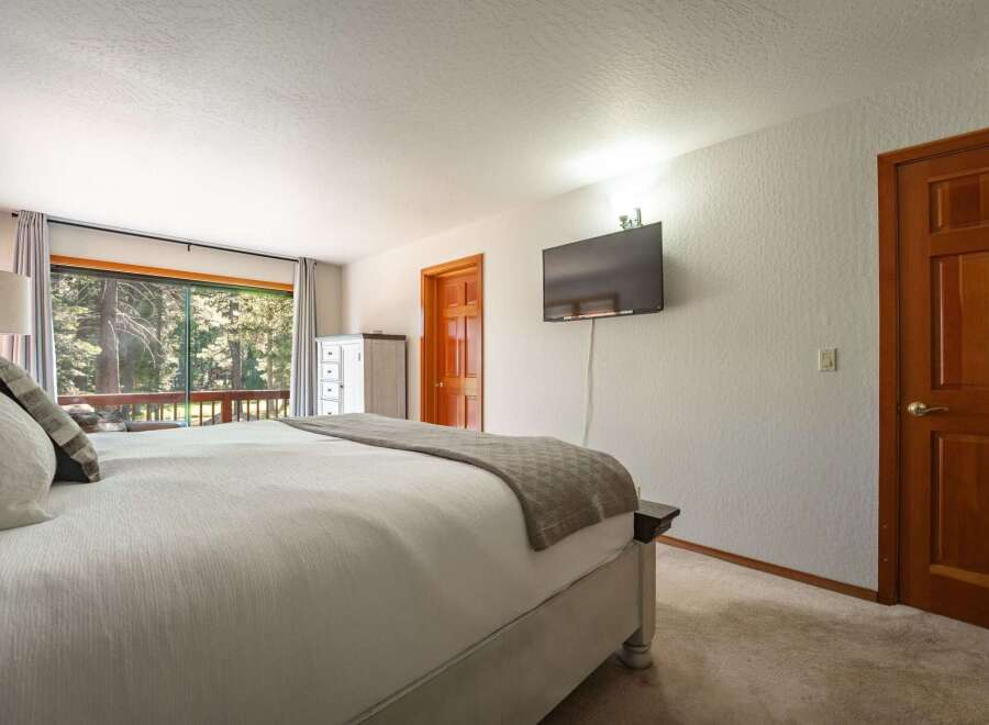 Experience serene living in this spacious bedroom, featuring a large bed with plush pillows and a cozy throw blanket.