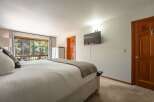 Experience serene living in this spacious bedroom, featuring a large bed with plush pillows and a cozy throw blanket.