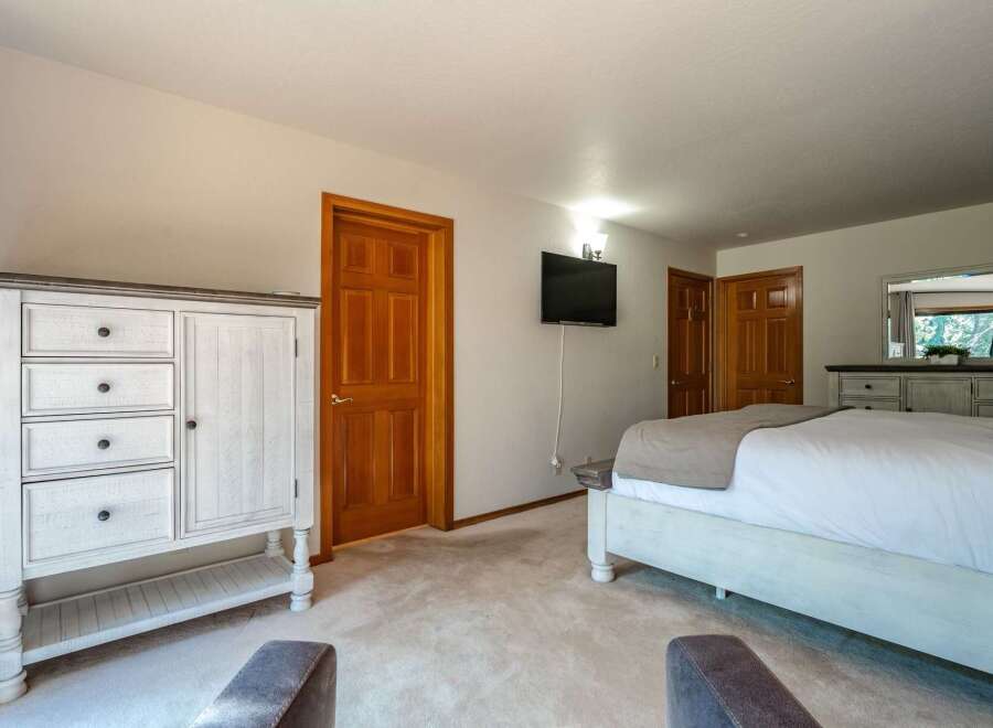 This spacious bedroom features a large white dresser with ample storage and a matching bed frame, creating a cohesive and airy feel.