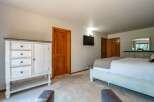 This spacious bedroom features a large white dresser with ample storage and a matching bed frame, creating a cohesive and airy feel.