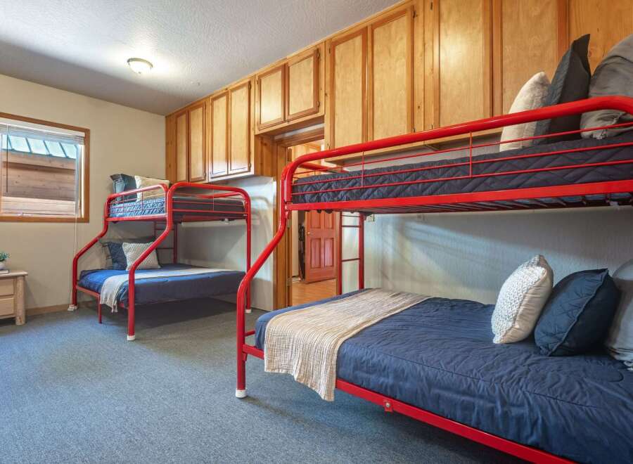 This charming bedroom features two sets of vibrant red bunk beds, perfect for accommodating multiple guests.