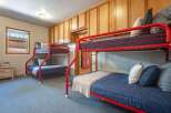 This charming bedroom features two sets of vibrant red bunk beds, perfect for accommodating multiple guests.