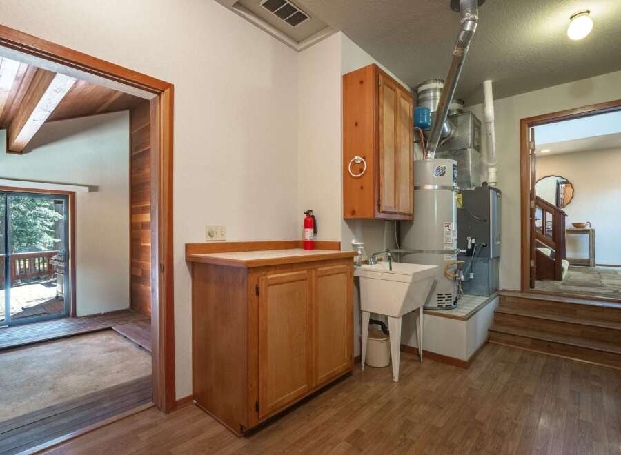 Discover practical living with this laundry area featuring a utility sink and ample cabinet space for storage.