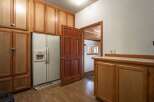 Discover ample storage with this kitchen's extensive wooden cabinetry, featuring a double-door refrigerator and a convenient built-in water dispenser.