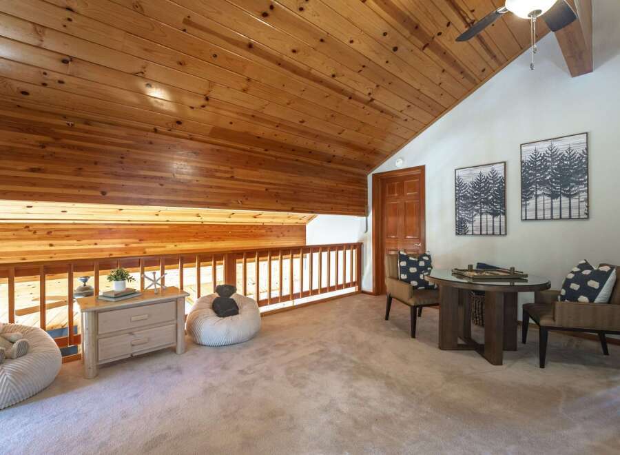 Experience cozy living in this charming loft space, featuring a warm wooden ceiling and a railing overlooking a lower level.