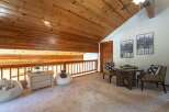Experience cozy living in this charming loft space, featuring a warm wooden ceiling and a railing overlooking a lower level.