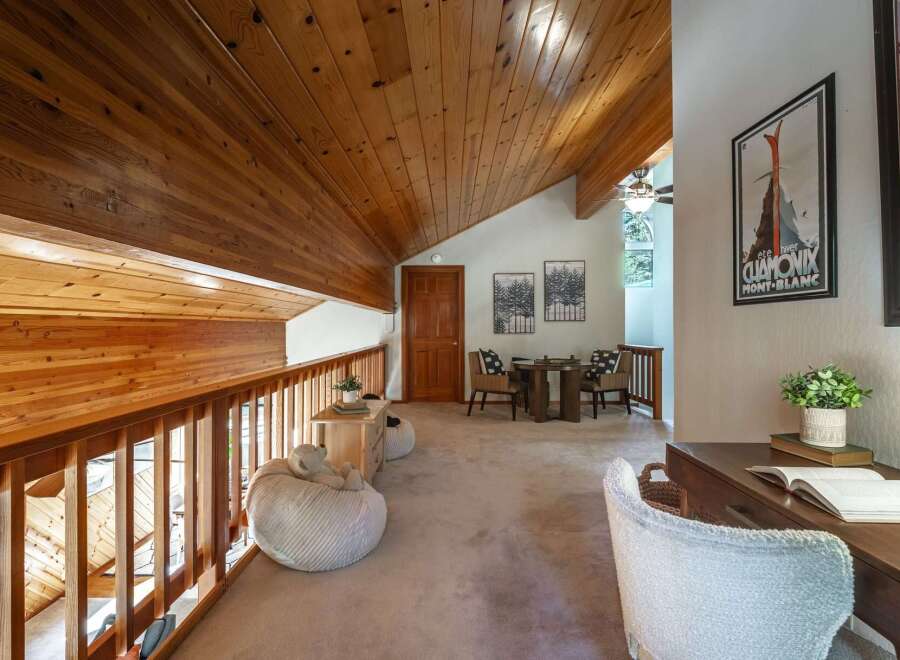 Experience rustic charm in this lofted living space featuring warm wood paneling on the vaulted ceiling and railings.
