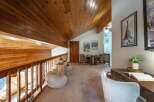 Experience rustic charm in this lofted living space featuring warm wood paneling on the vaulted ceiling and railings.