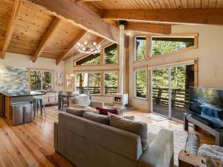 Experience the ultimate mountain retreat in this stunning cabin featuring a vaulted wood-beamed ceiling and a modern fireplace.