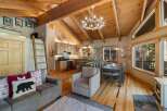 Experience rustic charm in this open-concept living space, featuring a vaulted wood-beamed ceiling and a cozy antler chandelier.