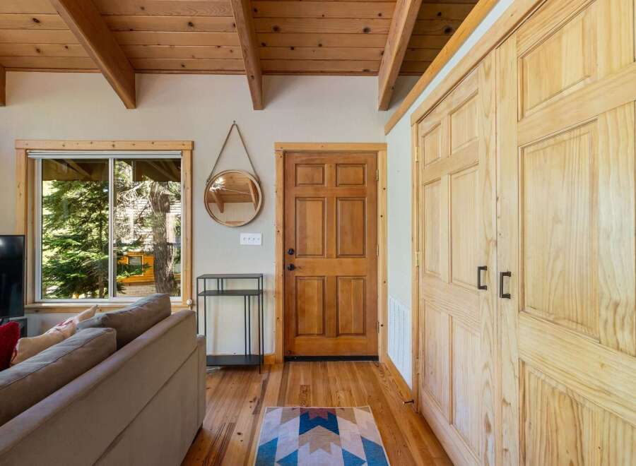Step into this charming cabin featuring a warm and inviting living space with a cozy sofa and a large window offering picturesque views of the surrounding trees.