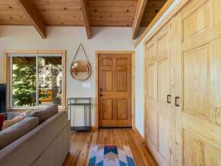 Step into this charming cabin featuring a warm and inviting living space with a cozy sofa and a large window offering picturesque views of the surrounding trees.