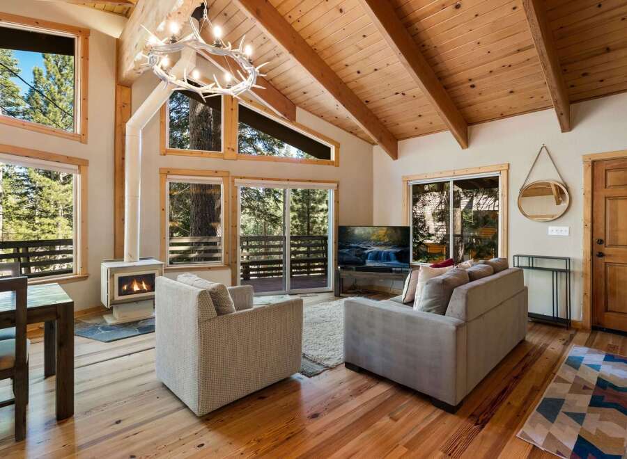 Experience cozy living in this mountain retreat featuring a stunning antler chandelier and a modern fireplace.