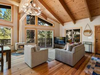 Experience cozy living in this mountain retreat featuring a stunning antler chandelier and a modern fireplace.